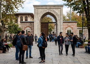 Üniversite kampüsünde yürüyen ve sohbet eden genç öğrenciler.