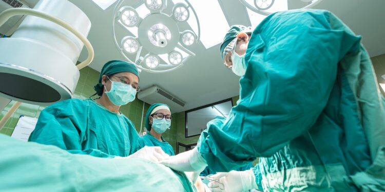 Yeşil giyimli cerrahlar ameliyathane lambaları altında operasyon gerçekleştiriyorlar.