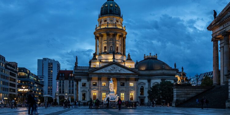 Akşam karanlığında Berlin'deki Gendarmenmarkt meydanı ve tarihi yapıların aydınlatılmış görünümü.