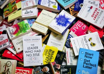 Farklı türlerde ve renklerde çok sayıda kitap üst üste yığılmış.