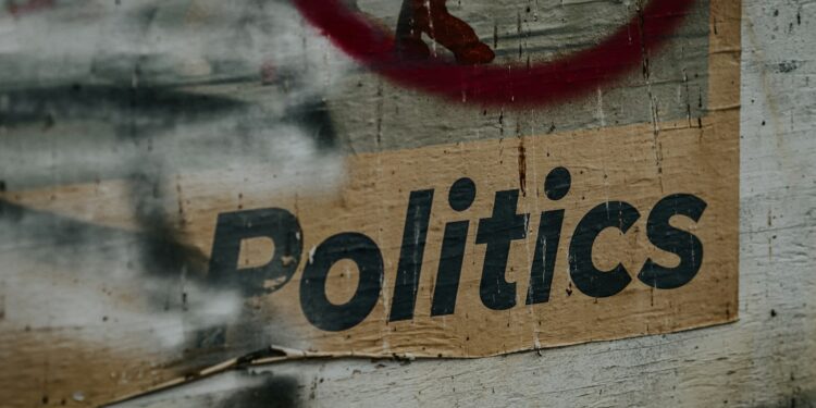 Üzerinde 'Politics' yazan, eskimiş ve yıpranmış bir sokak afişi.