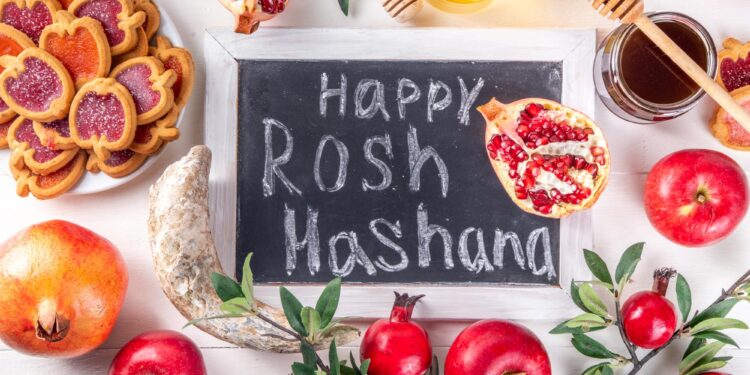 Üzerinde Happy Rosh Hashanah yazan kara tahta ve etrafında elmalar, nar ve bal.