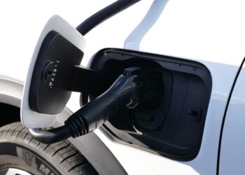 Beyaz bir elektrikli otomobilin şarj soketine siyah kablo takılıyor