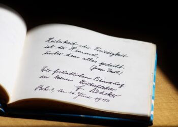Açık bir defter sayfasında Almanca el yazısı ve imza yer alıyor.