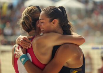 Plaj voleybolu maçından sonra birbirine sarılarak sevinen iki kadın sporcu.