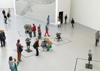 Geniş bir müzede sanat eserlerini ve sergileri gezen ziyaretçiler.
