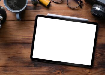 Ahşap masa üzerinde boş ekranlı bir tablet, kalem ve fincan.