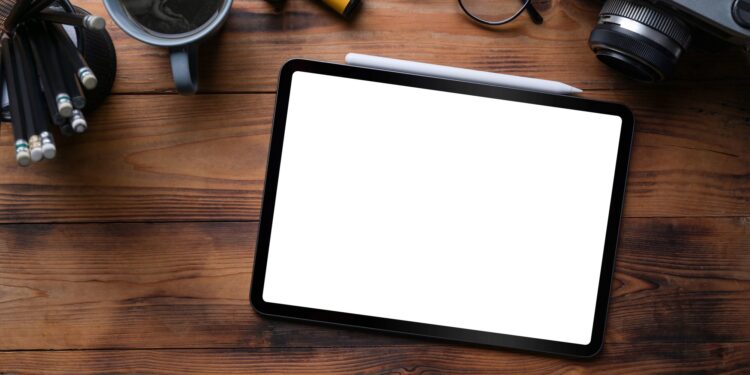 Ahşap masa üzerinde boş ekranlı bir tablet, kalem ve fincan.