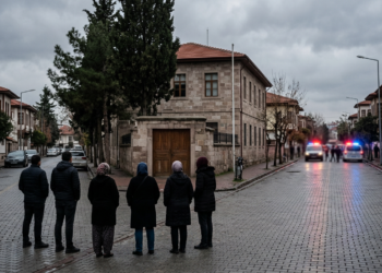 Turgutlu'da bir lisenin yakınında endişeyle bekleyen insanlar ve arka planda polis araçları.