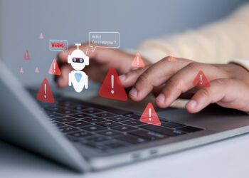 Laptop klavyesi üzerinde eller ve etrafta görünen kırmızı uyarı ikonları