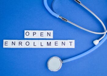Mavi zemin üzerindestetoskop ve İngilizce open enrollment yazılı harf küpleri.