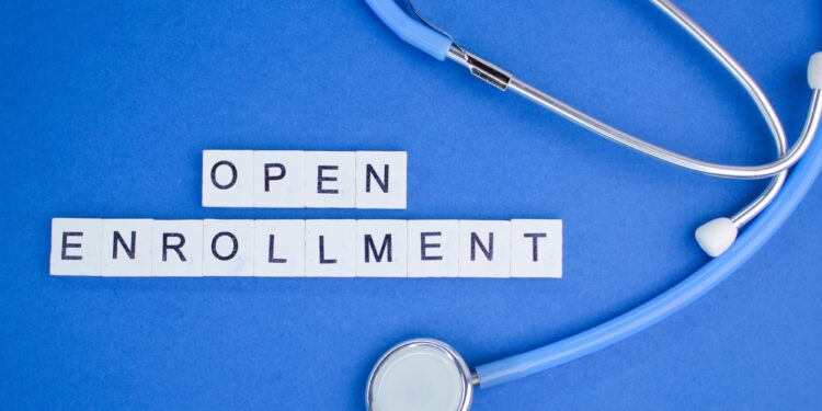 Mavi zemin üzerindestetoskop ve İngilizce open enrollment yazılı harf küpleri.