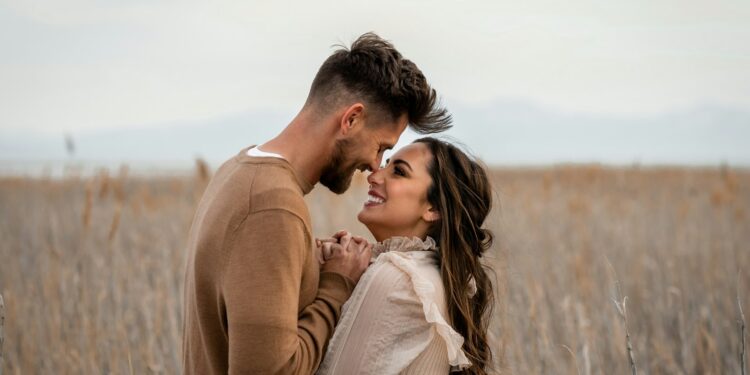 Açık havada birbirine sarılıp gülümseyen romantik genç bir çift.