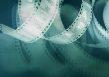 Eski bir film şeridi kıvrılarak duruyor, arka plan koyu yeşil.