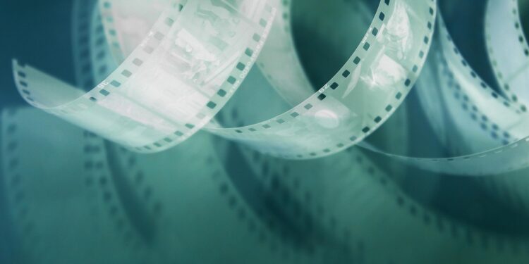 Eski bir film şeridi kıvrılarak duruyor, arka plan koyu yeşil.