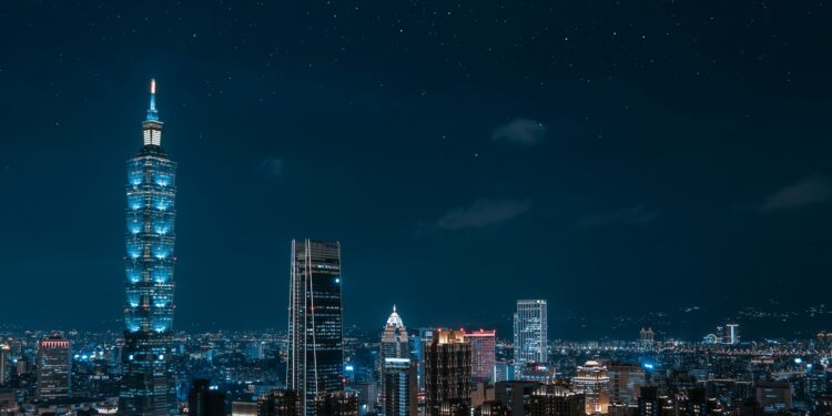 Gece vakti gökdelenlerin ve şehir ışıklarının uzaktan görünümü.