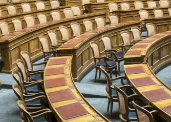 Ahşap masalı ve deri sandalyeli boş parlamento genel kurul salonu.